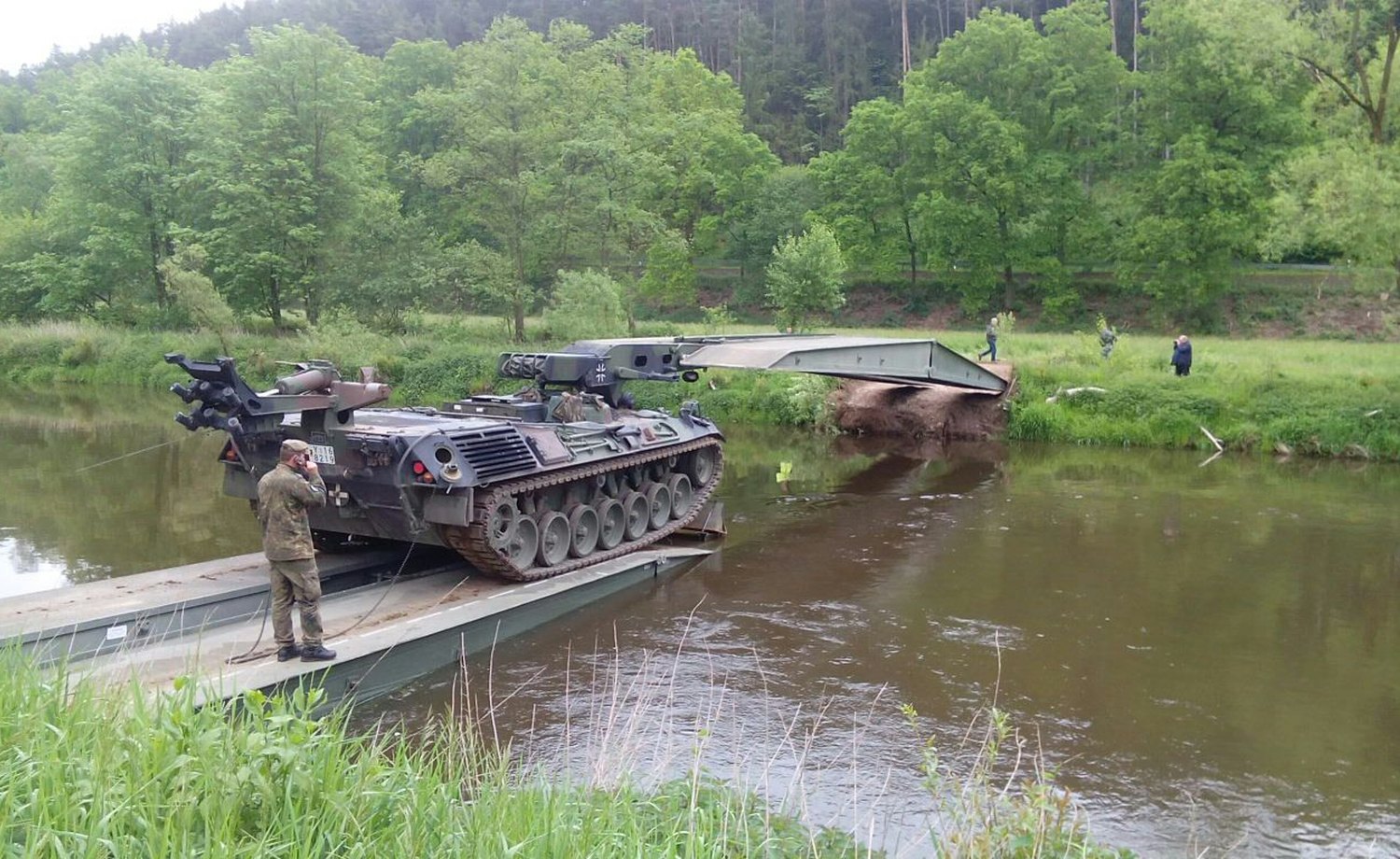 Militärisches Fahrzeug vollständig sichtbar bei Gewässerüberquerung und Brückenlage